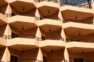 Bina aydınlık terracotta. Balkonlar ve bilgi pencereleri. Aynı mimari öğeler. Oteller ve oteller binaların örnekleridir. Otelin duvarlarında güneşli bir gün