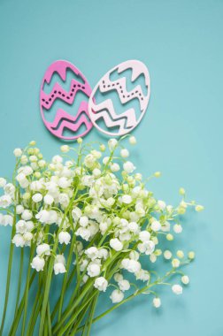 Çiçek mavisi arka plan ve taze çiçekler. Paskalya için bahar tebrik kartı. Bir buket nilüfer çiçeği ve bir hediye, yumurta..