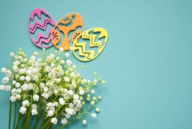 Çiçek mavisi arka plan ve taze çiçekler. Paskalya için bahar tebrik kartı. Bir buket nilüfer çiçeği ve bir hediye, yumurta..