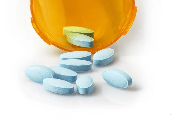 Small blue tablets spilling out of prescription container — Stock Photo, Image