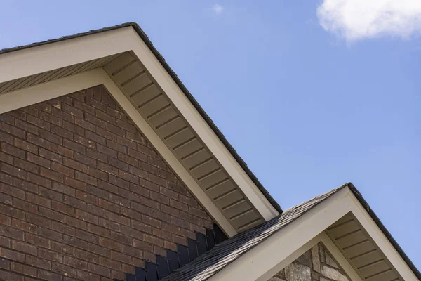 Tetto che mostra soffit sulla parte anteriore di una casa in mattoni e pietra . — Foto Stock