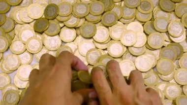 Bir çift el bir yığın Meksika sikkesiyle eğleniyor.