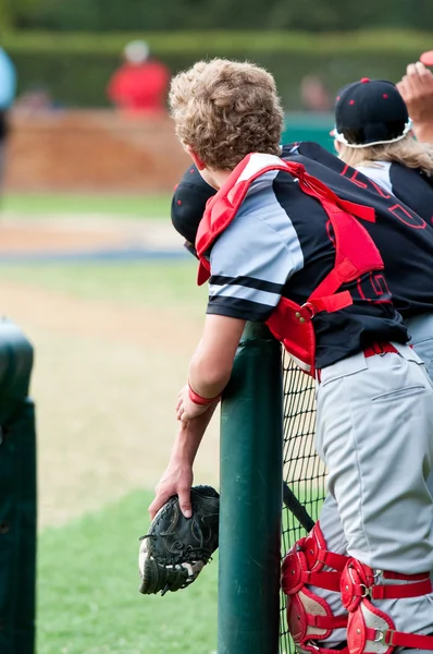 Baseball catcher leaning over dugout fence — ストック写真