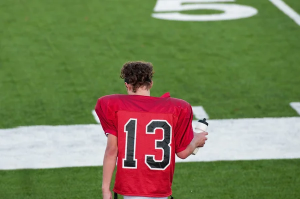 Youth football player on sidelines — ストック写真