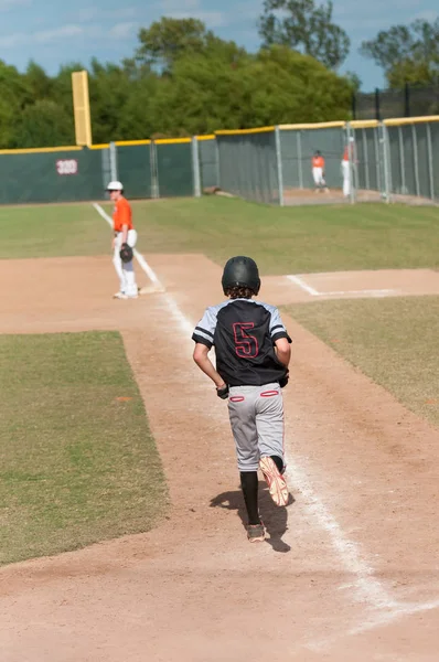 Kid basebollspelare tar första bas — Stockfoto