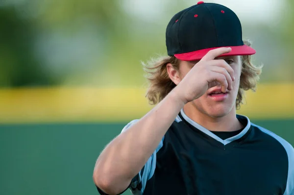High School baseballista chwytając brzeg kapelusza. — Zdjęcie stockowe