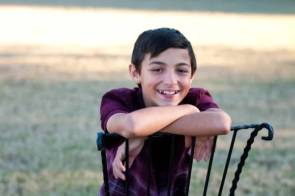 Portret van schattige jonge jongen, zittend in een stoel buiten. — Stockfoto