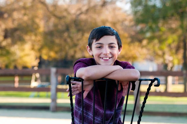 Perfil retrato de menino bonito sentado em uma cadeira ao ar livre . — Fotografia de Stock