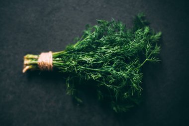 Koyu bir granit masada bir demet dereotu.