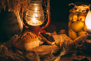 Ahşap bir tahtanın üzerinde mum ışığında reçelli dilimlenmiş ekmek. Kırsal atmosfer burada. Fotoğraf üstten.