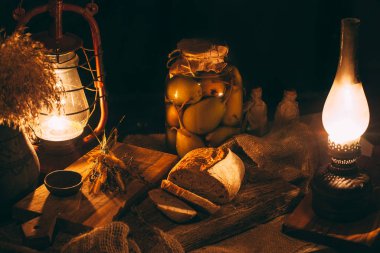 Mum ışığında dilimlenmiş taze pişmiş ekmek. Tahtada ekmek var. Kırsal sıcak atmosfer