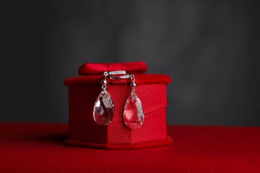 Kırmızı hediye kutusunda siyah arka planda küpeler.