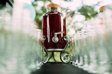 Musluklu kavanoz şenlik masasında. Kutunun ortasında meyve suyuyla dolu bir sürü bardak var..