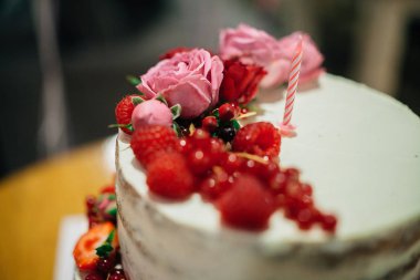 Birinci yaş gününde masanın üstünde böğürtlen ve çiçeklerle süslenmiş pasta.