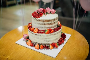 Böğürtlenlerle süslenmiş büyük pasta ve ilk doğum günü mumuyla süslenmiş çiçekler.