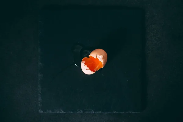 Huevo roto en una placa de pizarra en una vista de fondo negro desde la parte superior — Foto de Stock