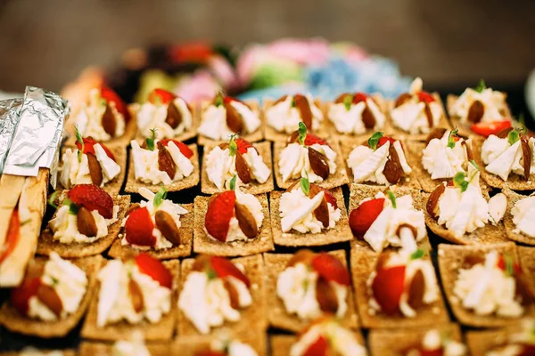 Süße Häppchen mit Frischkäse und Erdbeeren. Esstisch bei einer Open-Air-Party. — Stockfoto