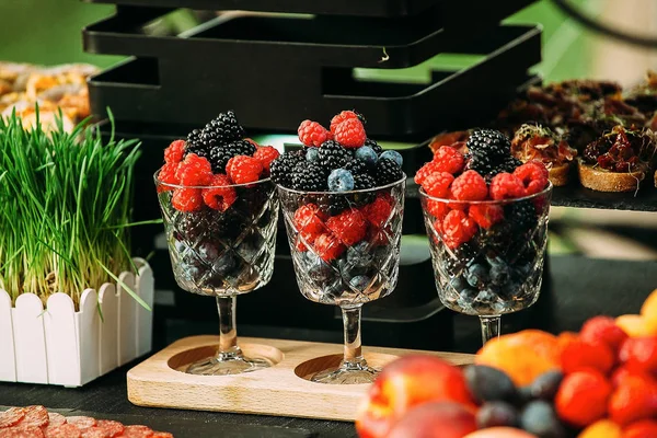 Gläser mit Beeren auf einem festlich mit Gras dekorierten Tisch. — Stockfoto