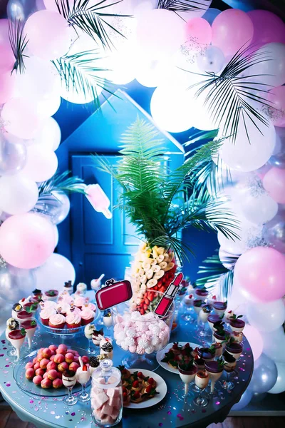 Beautifully decorated table with different cakes and sweets.Ice cream with jam and mint in glasses. Canapes with fruits. A large plate with pink bis. Jar with pink marshmallows. Palm with fruit. — Stock Photo, Image