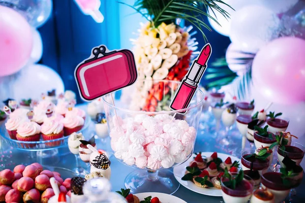 Ice cream with jam and mint in glasses. Fruit canapes. A large plate with pink bis. Jar with pink marshmallows. Palm fruit. — Stock Photo, Image