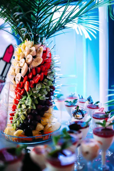 Palm tree with fruits: strawberries, kiwi, pineapple, banana, plum. Ice cream with jam and mint in glasses. — Stock Photo, Image