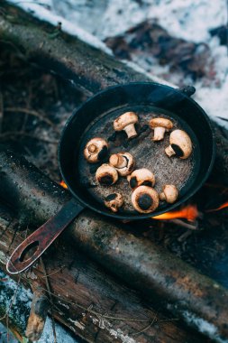 Ormanda tavada kızartılmış mantar. Doğada kızarmış yiyecek. Kış ormanında piknik. Açık ateşte yemek pişirmek. Yangında şampiyon.