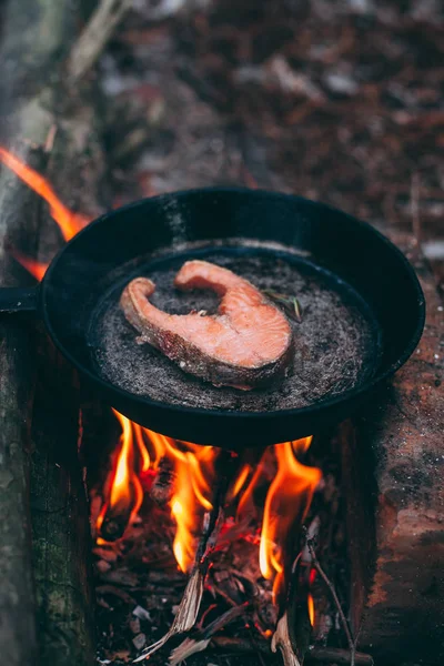 A piece of salmon in a pan over a fire. Cooking in nature. Grilled fish
