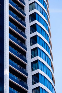 Modern konut binası koyu mavi, beyaz çizgili ve gökyüzüne karşı büyük cam pencereli. Gökdelen kapanıyor. İş oluşturma
