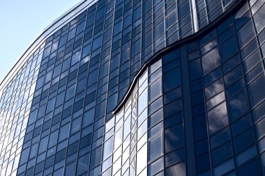 Mavi gökyüzüne karşı küçük bulutlu cam bina. Panoramik pencereli bir gökdelendeki iş ofisleri. Cam metal yapı.