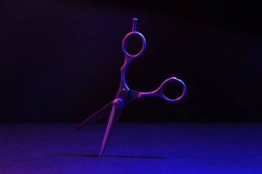 Siyah arka planda neon ışıkta makas yapmak. Kuaförün aleti..