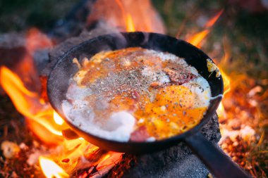 Ormanda tavada domuz pastırmalı sahanda yumurta. Kampta yiyecek var. Çırpılmış yumurta ve domuz pastırması. Bir sürü baharatlı yumurta. Piknik