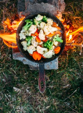 Karnabahar, brokoli ve tavada havuç. Açık ateşte yemek pişirmek. Açık hava yemekleri. Izgara sebze. Kamp gezisinde yemek.