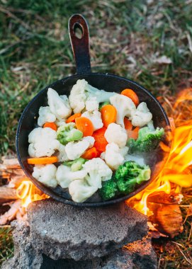 Karnabahar, brokoli ve tavada havuç. Açık ateşte yemek pişirmek. Açık hava yemekleri. Izgara sebze. Kamp gezisinde yemek.