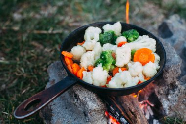 Karnabahar, brokoli ve tavada havuç. Açık ateşte yemek pişirmek. Açık hava yemekleri. Izgara sebze. Kamp gezisinde yemek.