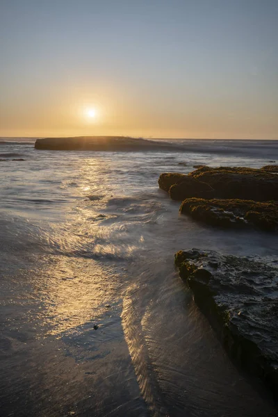 太阳从太平洋中央的水平线下落下来 在智利的野生海滩上 形成了美丽而多姿多彩的景观 柔和的阴影和橙色的反光 — 图库照片