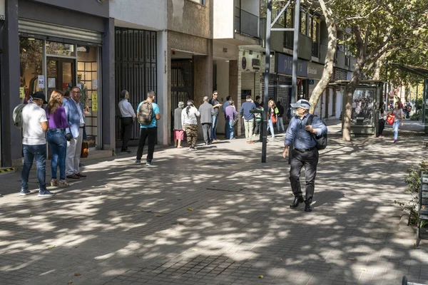Şehir: Santiago Ülke: 26 Mart 2020 Providencia sokaklarında Coronavirus hastalığı COVID-19 nedeniyle sokağa çıkma yasağından önceki son saatler boyunca banka ve dükkanlara girmek için bekleyenler