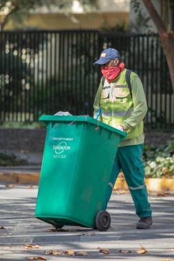 Şehir: Santiago Ülke: 2 Mayıs 2020 Coronavirus hastalığı enfeksiyonu sırasında CVID-19 enfeksiyonu sırasında Providencia caddelerini temizlerken endişeli gerçek göçmen temizlik işçisi
