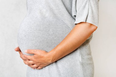 Karnında el ele tutuşan hamile bir kadın.