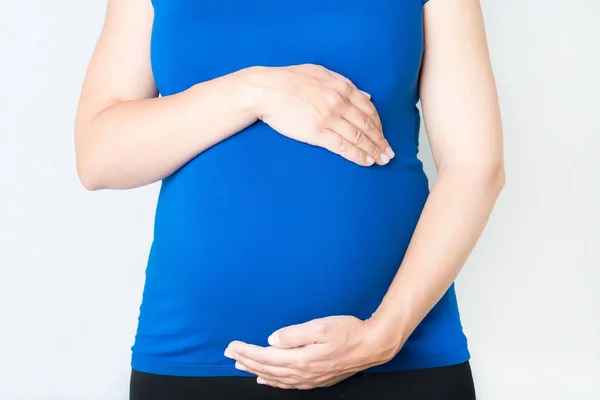 Беременная женщина держит руки на животе — стоковое фото