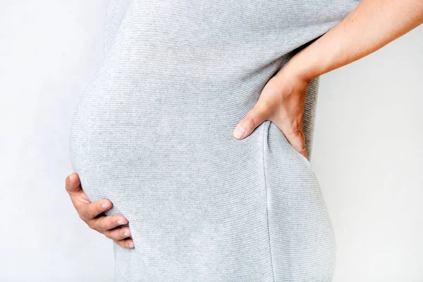 Gravid kvinna som håller händerna på hennes mage och rygg — Stockfoto