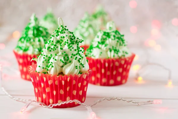 Christmas cupcakes with christmas tree shape, sparkler and lights on background