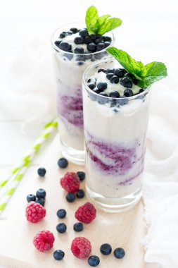 İki bardak taze yaban mersini dekore edilmiş smoothie çilek ve nane yaprakları ile