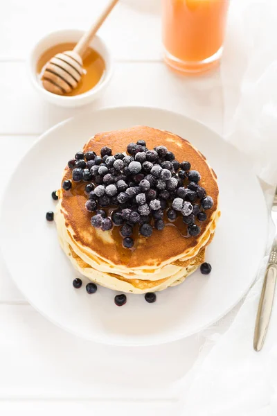 Stapel Pfannkuchen mit gefrorenen Blaubeeren und Honig — Stockfoto