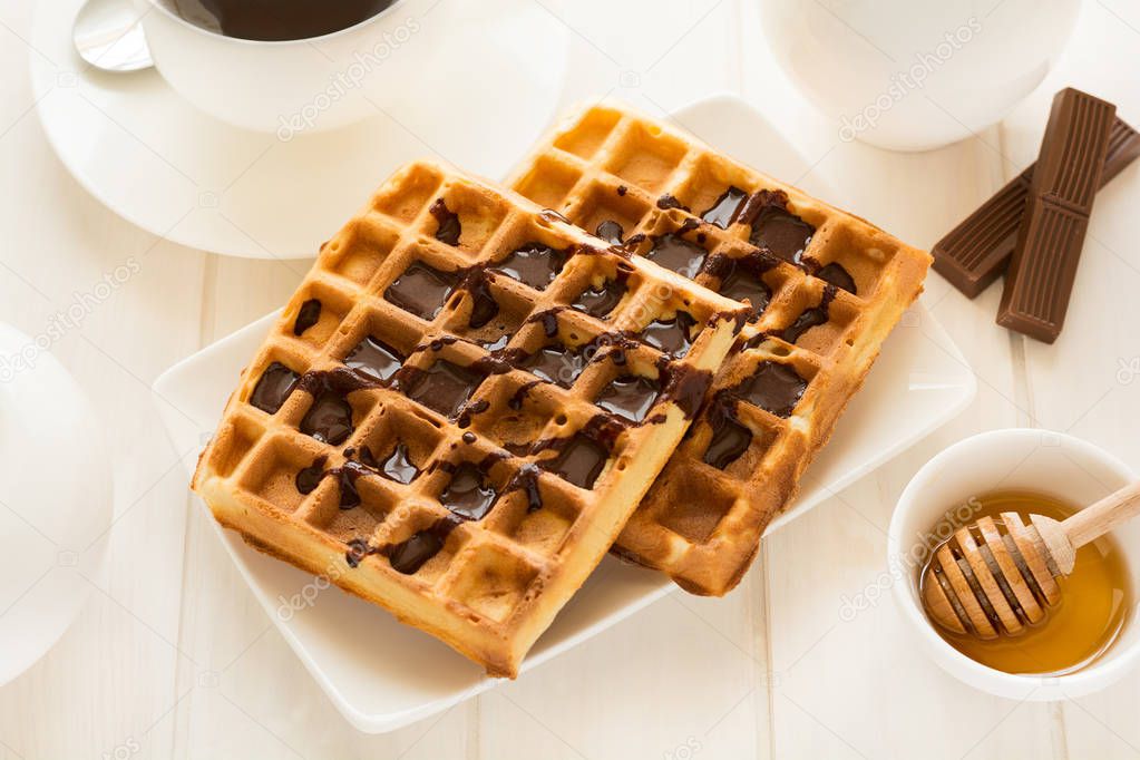 Traditional breakfast: coffee, belgian waffles with honey and chocolate sauce 