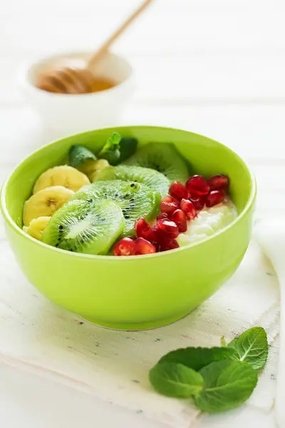 stock image Healthy breakfast: fresh cottage cheese with kiwi, banana, garnet seeds and honey decorated mint leaves 