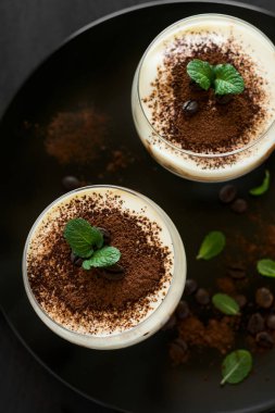 Geleneksel İtalyan tatlı tiramisu dekore edilmiş kakao, kahve çekirdekleri ve nane yaprakları