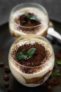 Geleneksel İtalyan tatlı tiramisu dekore edilmiş kakao, kahve çekirdekleri ve nane yaprakları 