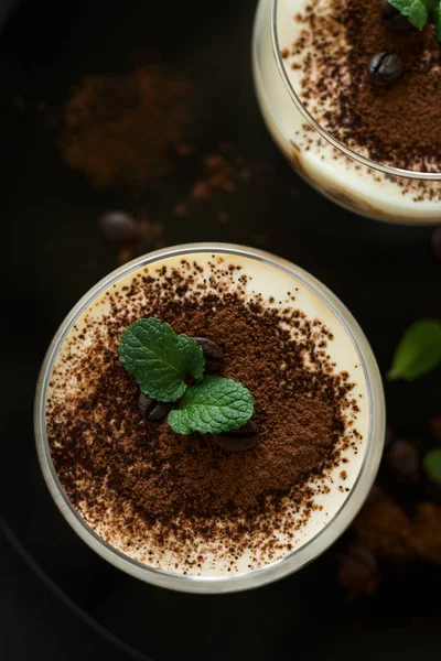 Traditional Italian dessert tiramisu decorated cocoa, coffee beans and mint leaves