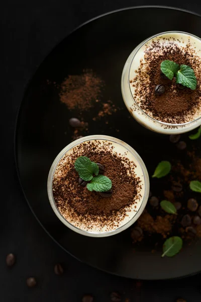 Traditional Italian dessert tiramisu decorated cocoa, coffee beans and mint leaves