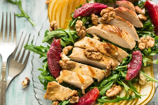 Salada de primavera fresca com peito de frango grelhado, rúcula, pêra e fatias de laranja e nozes — Fotografia de Stock